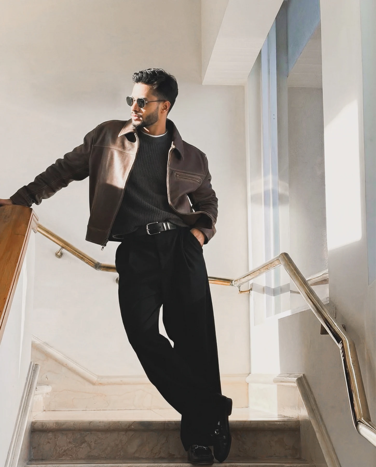 Rahul Manhar in a brown leather jacket on a sunlit staircase