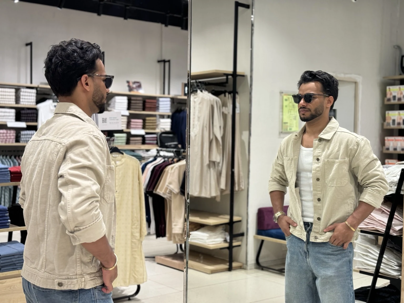 Rahul modelling a neutral overshirt in a fashion store mirror