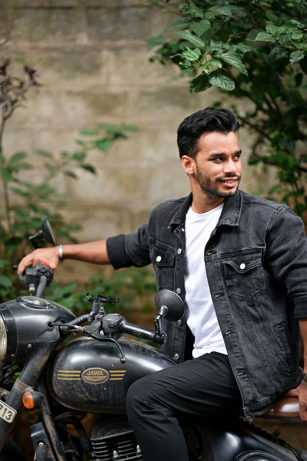 Rahul Manhar in a black denim jacket seated on a Jawa motorcycle